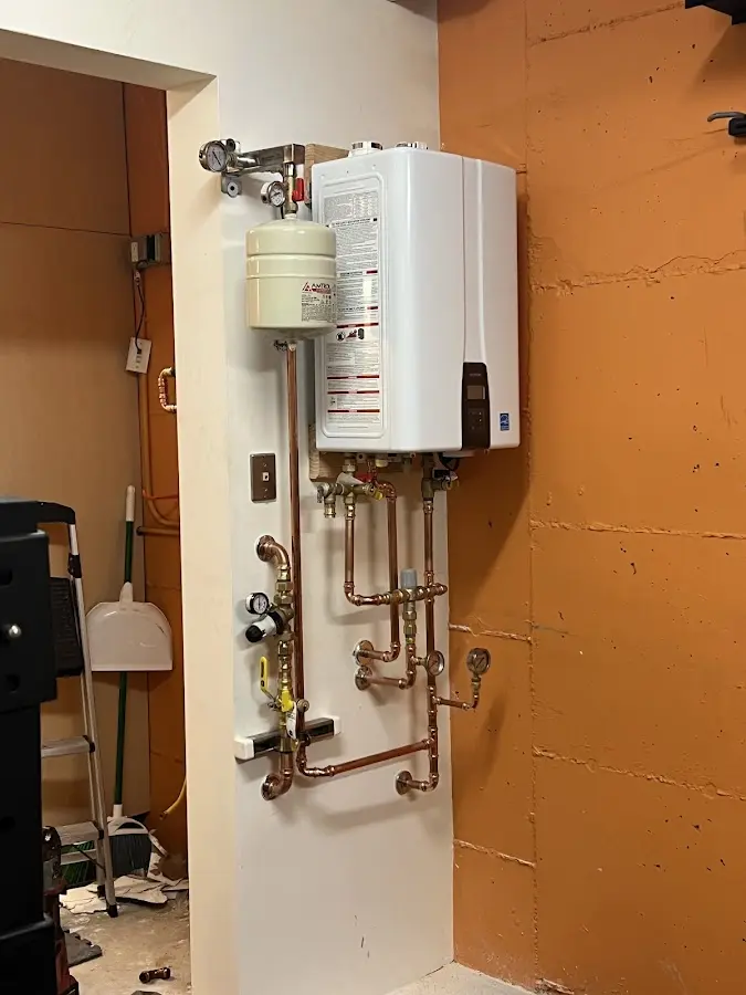 Plumbing technician inspecting water heater connections in Coe